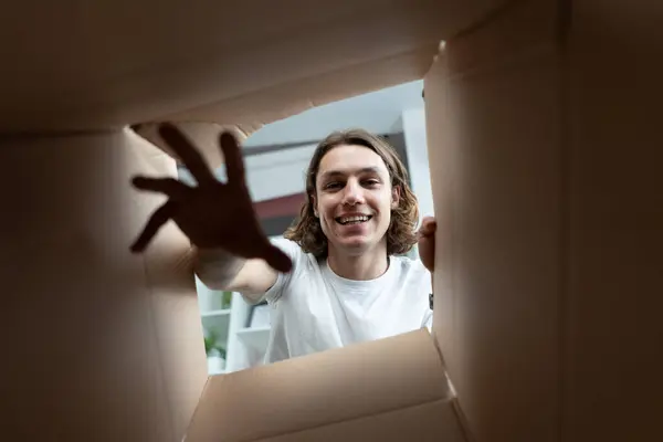 Joyful Man Unpacking Box Smiling Young Adult Gently Reaching Out lizenzfreie Stockbilder