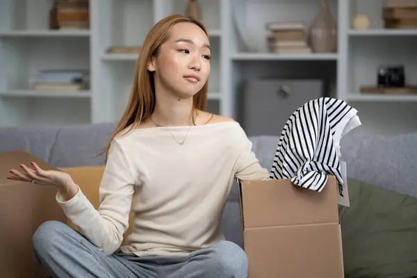 Young Woman Unpacking Clothes Expressing Disappointment Fashion Purchase Modern Living Stock Picture