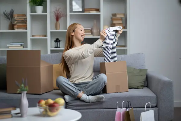 Happy Woman Unpacking Clothes Box Home Smiling Joyfully Living Room Stock Image