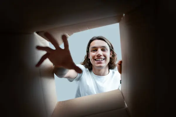 Joyful Man Unpacking Box Smiling Young Adult Gently Reaching Out lizenzfreie Stockbilder