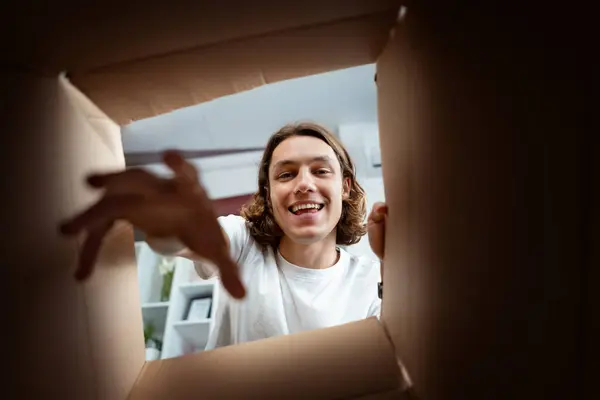Smiling Young Man Reaching Box Evoking Excitement Surprise Ideal Themes รูปภาพสต็อกที่ปลอดค่าลิขสิทธิ์