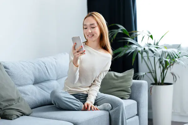 Young Woman Enjoying Time Couch Smartphone Modern Living Room Surrounded Stockbild