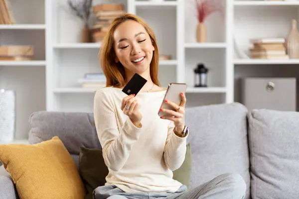 Щаслива Молода Жінка Використовує Смартфон Тримає Кредитну Картку Дивані Інтернет Ліцензійні Стокові Фото