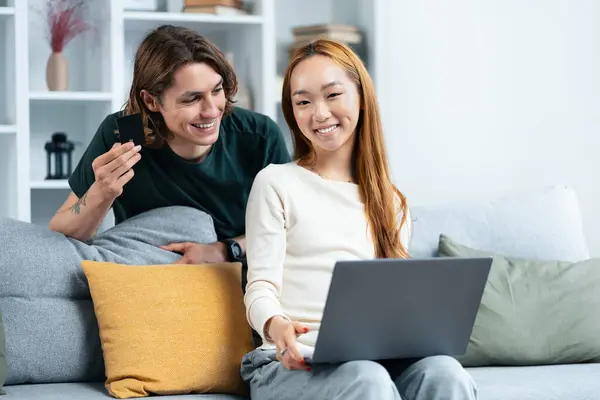 Happy Couple Shopping Online Together Home Young Man Holding Credit lizenzfreie Stockfotos