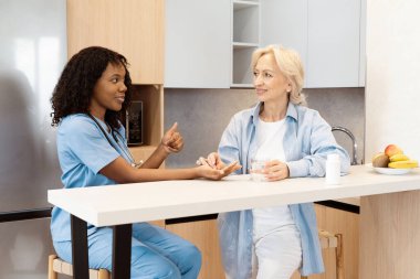 Yaşlı kadınların kan şekeri seviyelerini kontrol eden hemşire, sağlık hizmetlerinin altını çizen, destek veren ve bir evde bakım konsepti sunan hemşire.