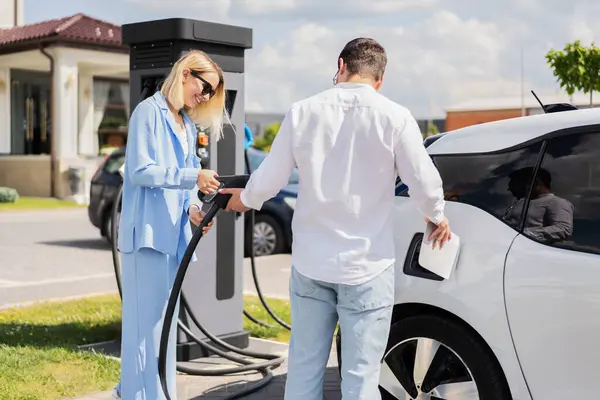 stock image Couple Charging Electric Car At Station On Sunny Day, Embracing Future Of Eco-Friendly Transport And Renewable Energy