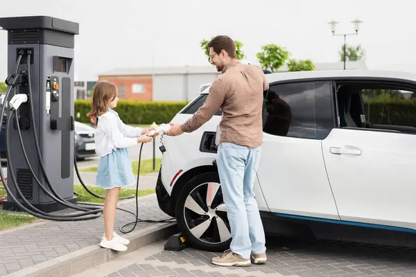 stock image Father And Daughter Charging Electric Car At Charging Station, Promoting Sustainable And Eco-Friendly Transportation. The Image Depicts A Family Moment Emphasizing The Use Of Renewable Energy 