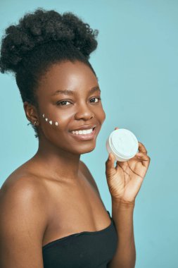 Mavi Arkaplan Karşısında Cilt Kremi Tutan Kadın