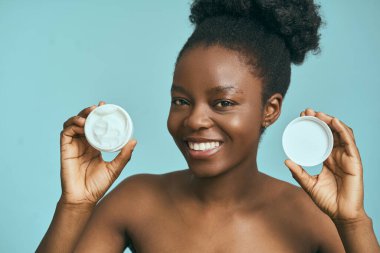 Mavi Arkaplan Karşısında Cilt Kremi Kavanozu Tutan Kadın