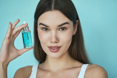 Cilt bakımı. Mavi Serum Şişesi, Mavi Arkaplan, Cilt Ürünleri ve Temiz Cilt Karşıtı Kadın