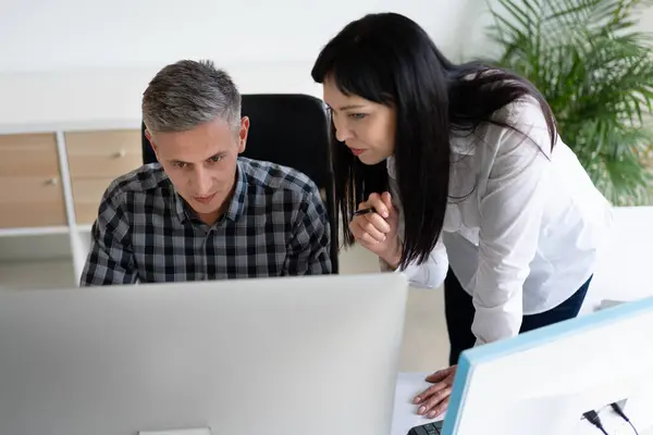 Stock image Colleagues Collaborating On Project At Computer In Modern Office Environment, Emphasizing Teamwork, Focus, And Professionalism