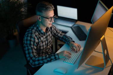 Ofisteki bilgisayarda geç saate kadar çalışan adam