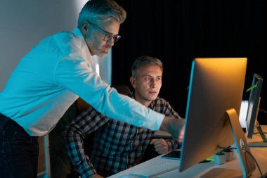 Proje üzerinde çalışan, odaklanarak ve ekip çalışmasıyla bilgisayar ekranı üzerinde çalışan ortaklar. Akşam Işığı Ofis Ortamı. Takım çalışması, işbirliği, iş desteği kavramı
