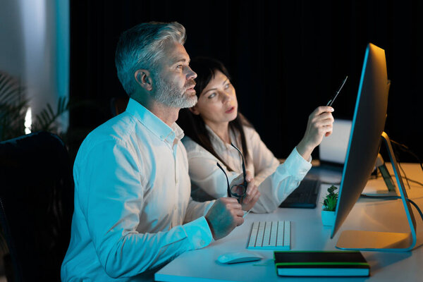 Two Business Professionals Collaborating Night Office Analyzing Data Computer Teamwork Royalty Free Stock Photos