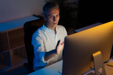 Masada geç saatlere kadar çalışan, Bilgisayar ekranına odaklanan adam
