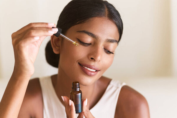 Skincare Routine: Woman Applying Facial Serum. A Serene Moment Emphasizing Self-Care, Beauty, And Wellness. Healthy Skin And Relaxation Through Cosmetics And Essential Oils.