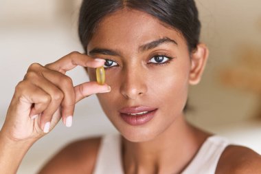 Omega-3 Eki. Balık Yağı Kapsülü Tutan Güzel Kadın Sağlık Yardım ve Yaşam Tarzını Vurguluyor. Parlak, davetkar atmosfer Sağlığı ve Besleyici Sezgileri Vurguluyor.