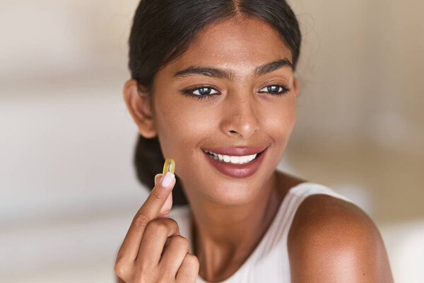 Woman Diet Supplement. Smiling Woman Holding Vitamin Capsule, Highlighting Health, Wellness, Beauty, Self-Care, Nutrition, Positive Lifestyle Choices, And Daily Healthy Habits.