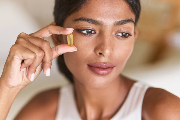 Nutrition. Close-Up Of Woman Holding Yellow Capsule Tablet, Emphasizing Health, Wellness, And Skin Care. Ideal For Supplements, Vitamins, And Self-Care Concepts.