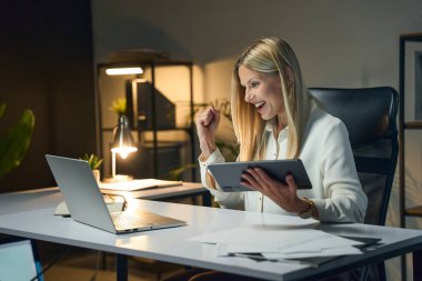Modern ofis ortamında uzaktan çalışırken Başarı Kutlaması Yapan Profesyonel Kadın. Kurumsal Ayarlarda Heyecan ve Başarı. İş-Hayat Dengesi ve Kariyer Büyümesi Konsepti 