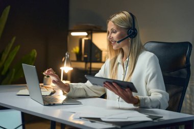 Profesyonel Müşteri Hizmetleri Ajanı Modern Çalışma Alanında Çevrimiçi İletişim Kuruyor. Laptop ve Tablette Kadın Çoklu Görev Uzaktan Çalışmayı, Teknoloji Kullanımını Temsil Ediyor