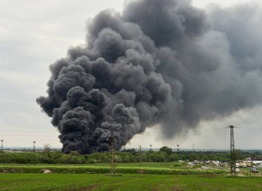 Black toxic smoke from industrial fire burning platic and rubber waste, air pollution by poisonous ingredients