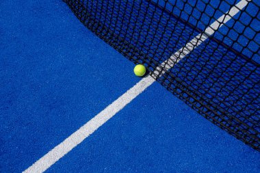 Mavi raket tenis kortunda top ağlara yakın.
