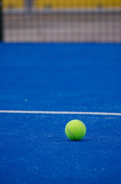 a paddle tennis ball on a blue artificial grass court
