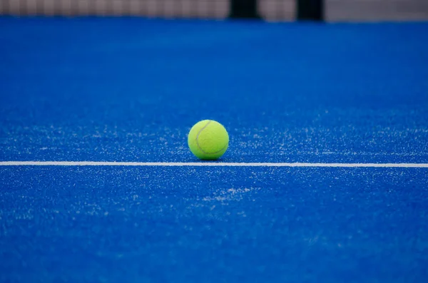 stock image paddle tennis ball on the line of a blue paddle tennis court, racket sports concept