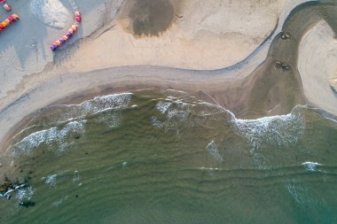 Yazın gün batımında kumlu sahildeki renkli kulübelerin hava manzarası.