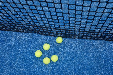 Mavi raket tenis kortu ve kalenin yanında beş top.