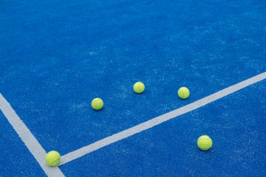 Mavi raket tenis kortunun orta çizgisinde beş top, seçici odaklanma