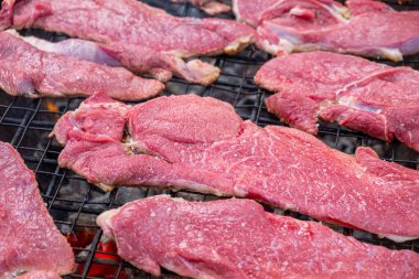 Seçici odak noktası, ızgaradaki çiğ dana biftekler.