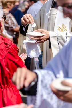 Selective focus, catholic priests distributing the communion wafer clipart