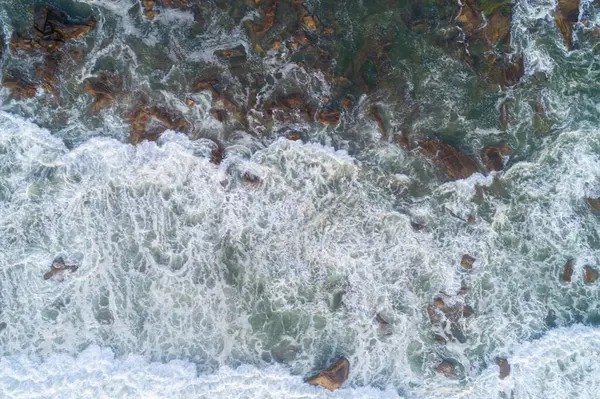 Kırık Dalgaların Köpüğüyle Kayalık Bir Sahil Şeridinin Hava Aracı Fotoğrafı — Stok fotoğraf