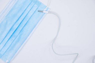 Yüz maskesi ve akıllı telefon kulaklığından çıkan mini jack konnektörü. Beyaz arkaplan.