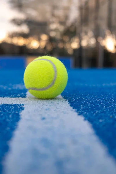 Gün batımında mavi raket tenis kortunun beyaz çizgisindeki topun seçici odağı