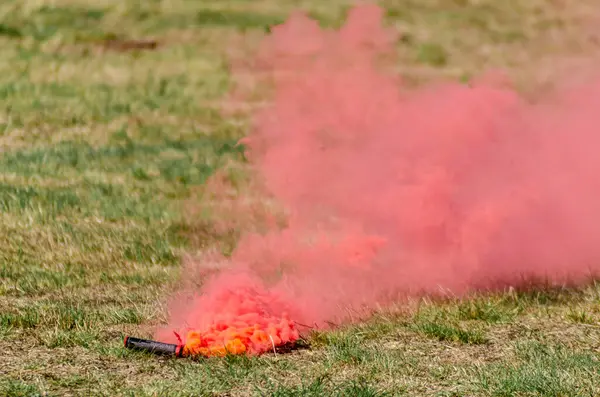 red smoke flare lying on a grassy field