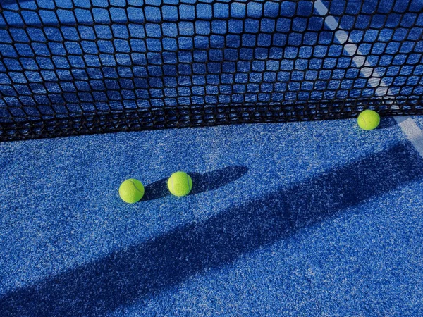 three paddle tennis balls near the net of a paddle tennis court, racket sports concept