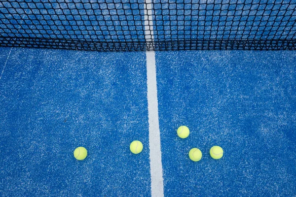 Mavi raket tenis kortu, yanında beş top, raket spor konsepti.