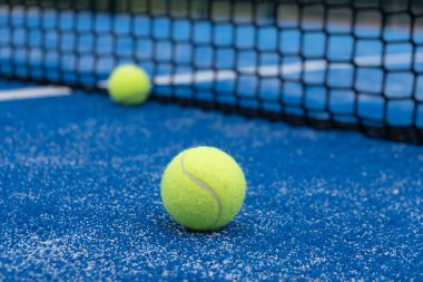 Mavi bir Padel tenis kortunun yanında iki top raket spor konsepti.
