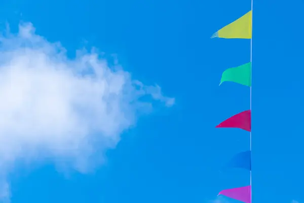 decorative colored pennants with a blue sky background and a cloud