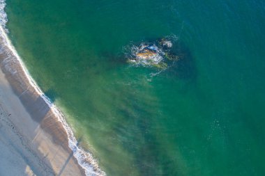 Bir kaya parçasıyla kumsal manzarası.