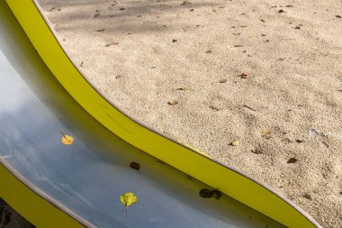 Sonbaharda bir çocuk parkında sarı bir slaytın ayrıntıları