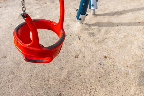 detail of a red metal swing on a children\'s playground