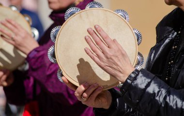 hands of a woman playing a tambourine at a Galician traditional music festival clipart