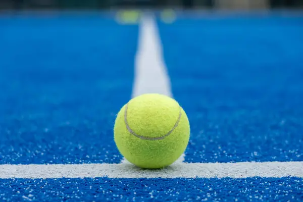 selective focus of a paddle tennis ball on the line of a blue paddle tennis court, racket sports