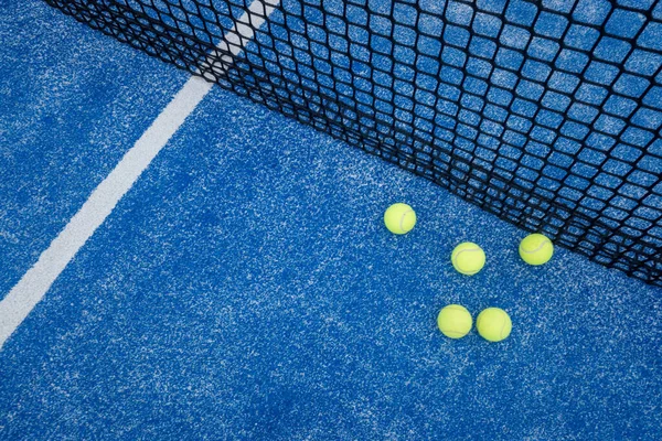 five paddle tennis ball on the net of a blue paddle tennis court