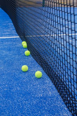 Yapay çimenli mavi bir tenis kortunda toplar.