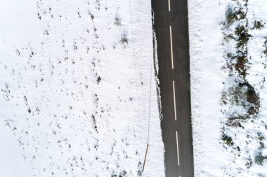 Zenital hava aracı karlı bir kırsal bölgedeki bir yola bakıyor.